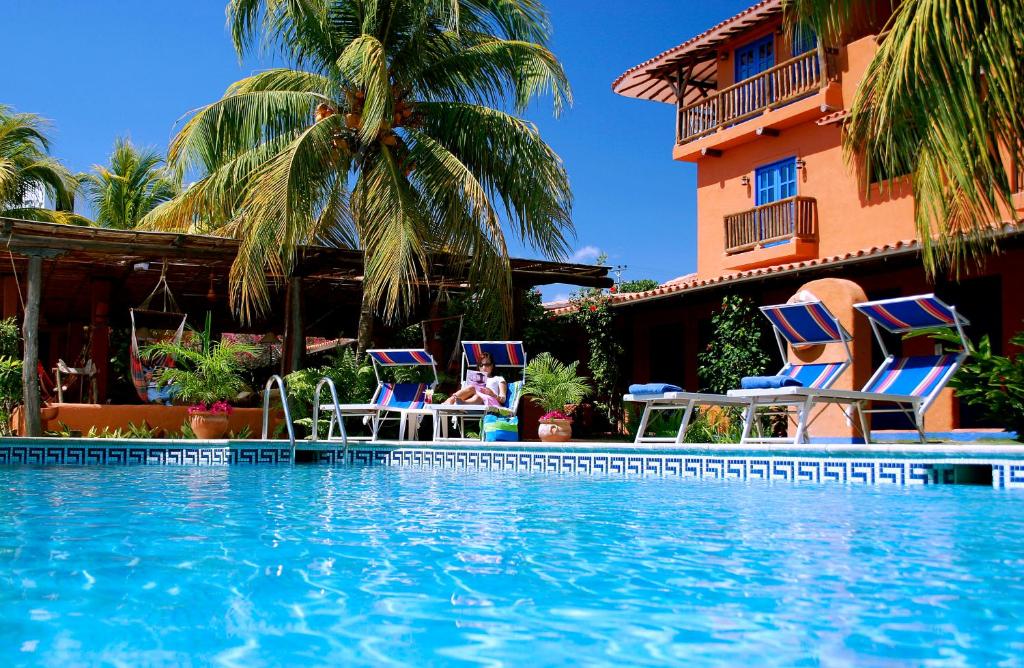La LomaHotel Costa Linda Beach的一个带椅子的游泳池和一座建筑的度假胜地