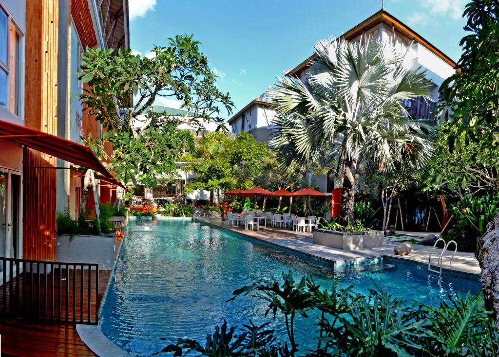 库塔落日余晖大道哈里斯度假酒店的一座拥有树木和建筑的度假村内的游泳池