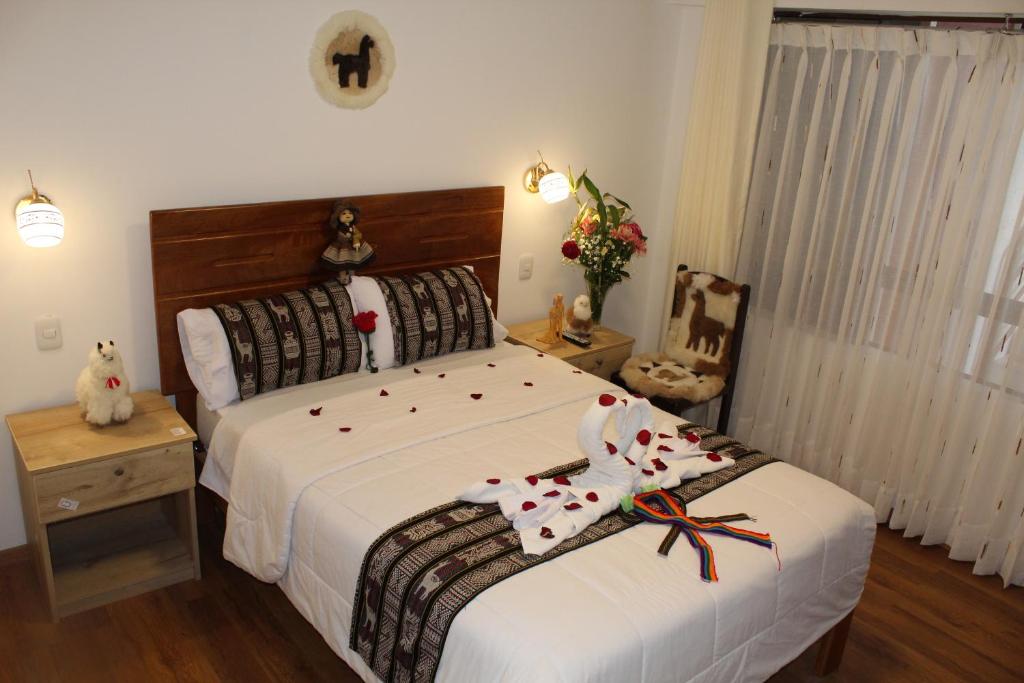 库斯科Cusco Hostal Qolla Wasi的一间卧室配有一张带白色床单的大床