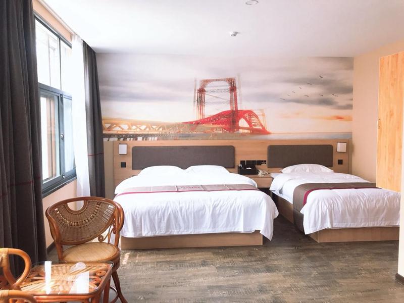 威海尚客优精选山东威海荣成市成山大道大润发店的酒店客房设有两张床,墙上挂有绘画作品