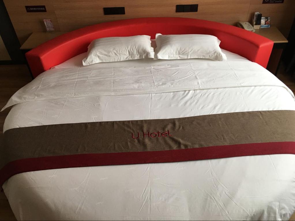 Duanlutou尚客优精选河北邢台南宫市段芦头镇店的一张有红色床头板的床,上面写着酒店字