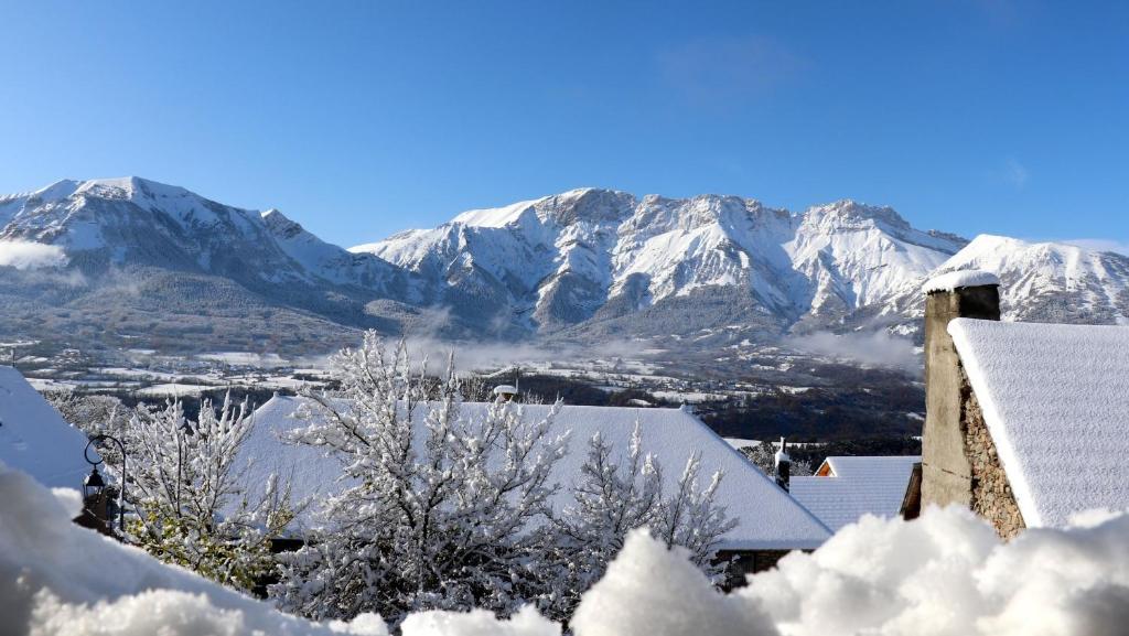 尚普索地区圣博内Le Cairn Chambres & Table d'hôtes的远处的雪覆盖的山脉,有房子