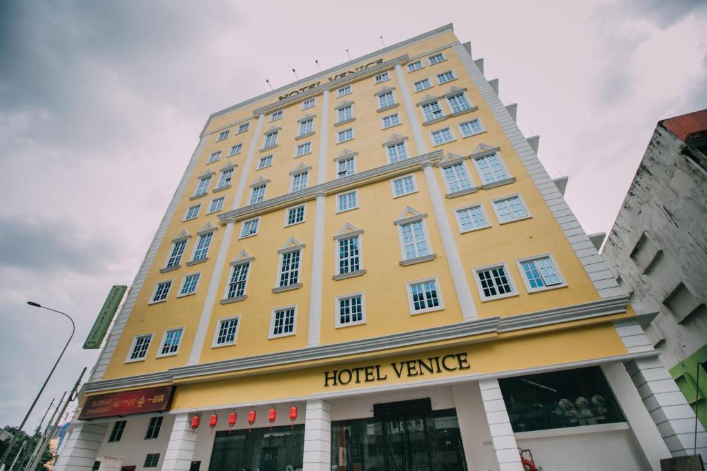 吉隆坡Hotel Venice的一座黄色的大建筑,带有酒店式房车