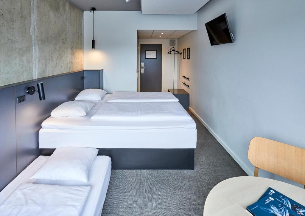 奥胡斯Zleep Hotel Aarhus Viby的带三张床和电视的客房