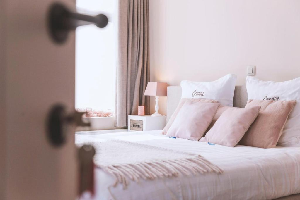 尼乌波特Jeanne的一间卧室配有带白色床单和枕头的床。