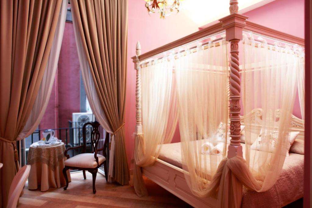 那不勒斯兰辉派宫酒店的一间卧室配有带窗帘的天蓬床