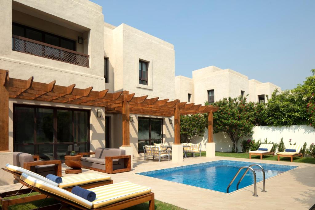 迪拜Dubai Creek Club Villas的一个带游泳池和房子的后院