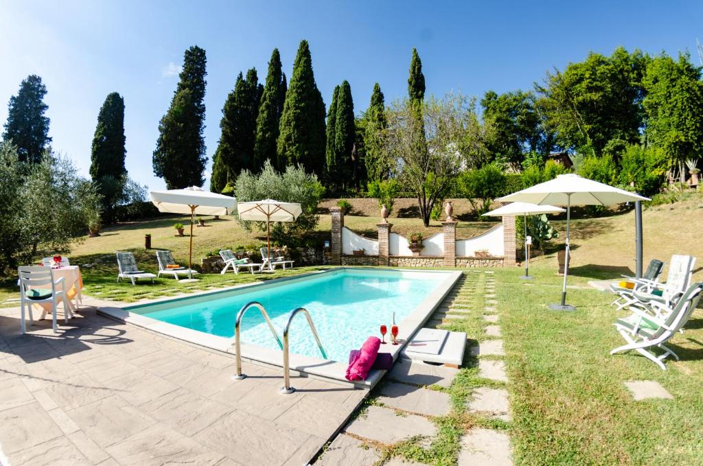 UzzanoVilla al Borghetto的庭院内的游泳池,配有椅子和遮阳伞