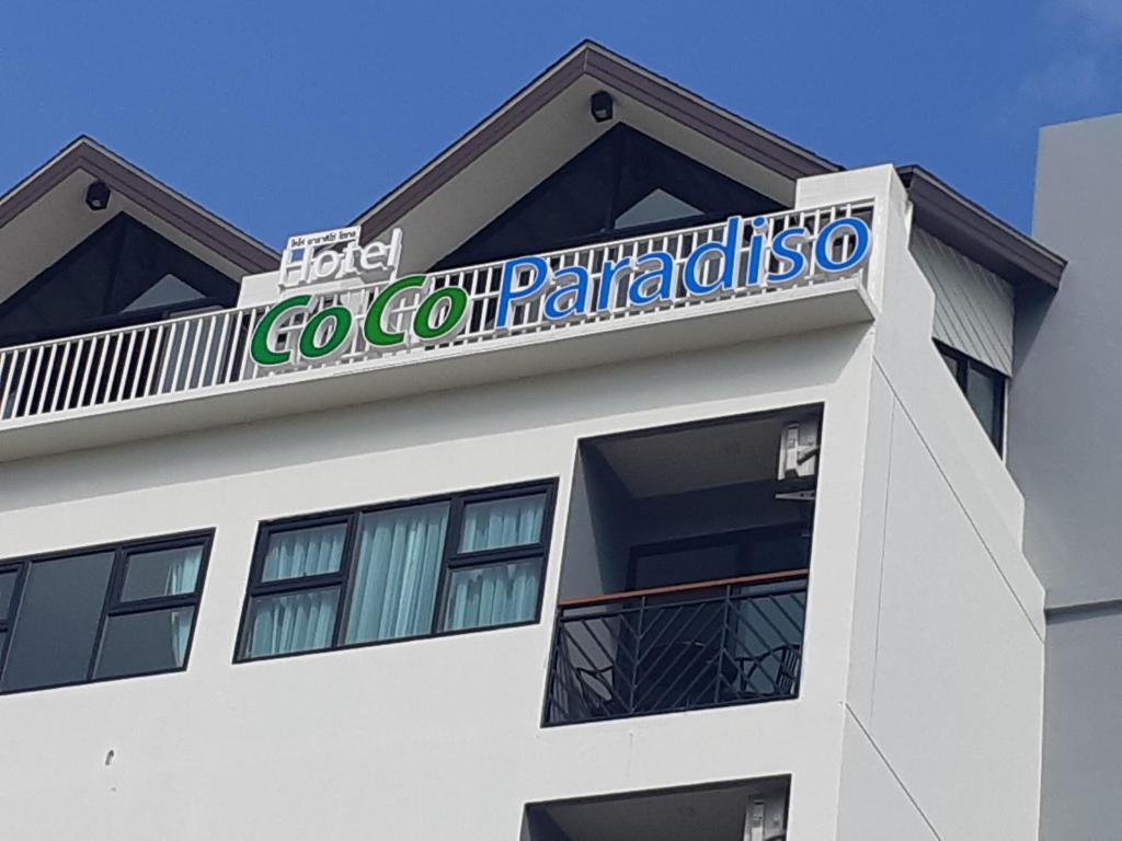 普吉镇Coco Paradiso Phuket SHA的白色的建筑,上面有标志