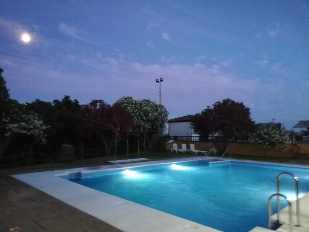 莱佩Hotel La Barca的夜间游泳池,月亮在顶端