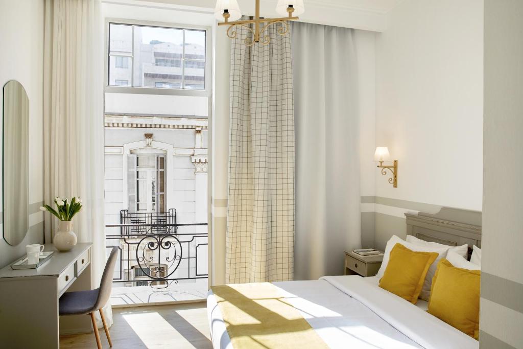 塞萨洛尼基卢森堡酒店的一间卧室配有一张床、一张书桌和一个窗户。