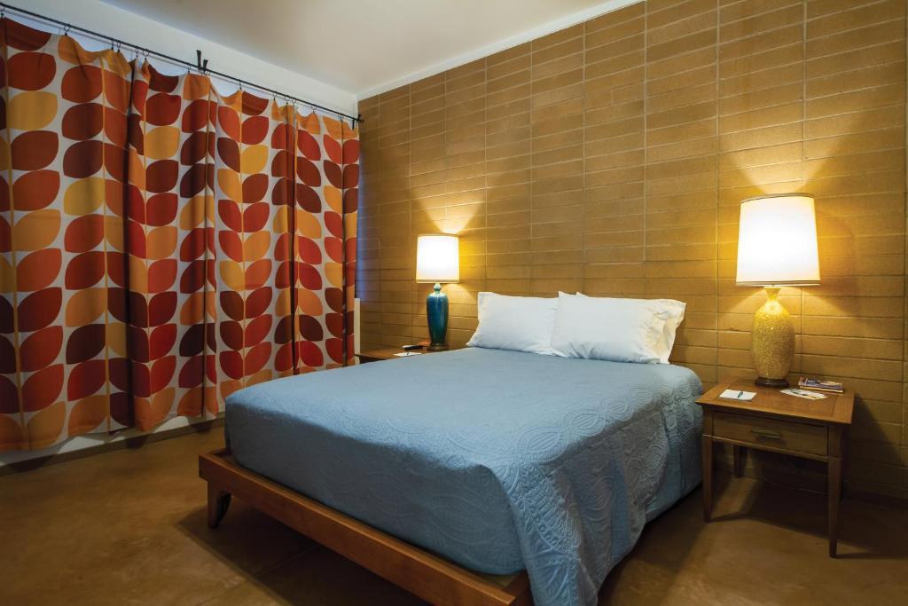土桑克利夫顿市区酒店的一间卧室配有一张床、两盏灯和窗帘