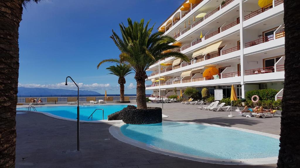 圣地亚哥港Playa de la Arena Apartment的一座大型酒店,设有游泳池和棕榈树