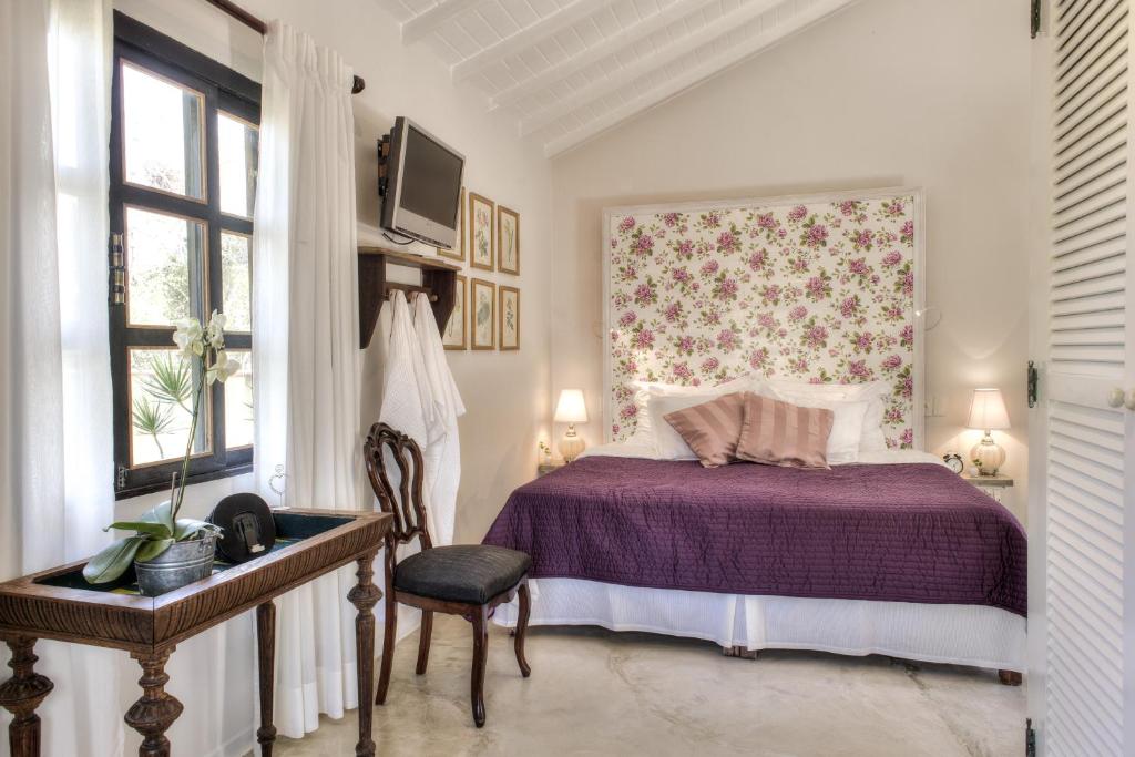 布希奥斯巴尔萨泽别墅酒店的一间卧室配有一张紫色的床和一把椅子