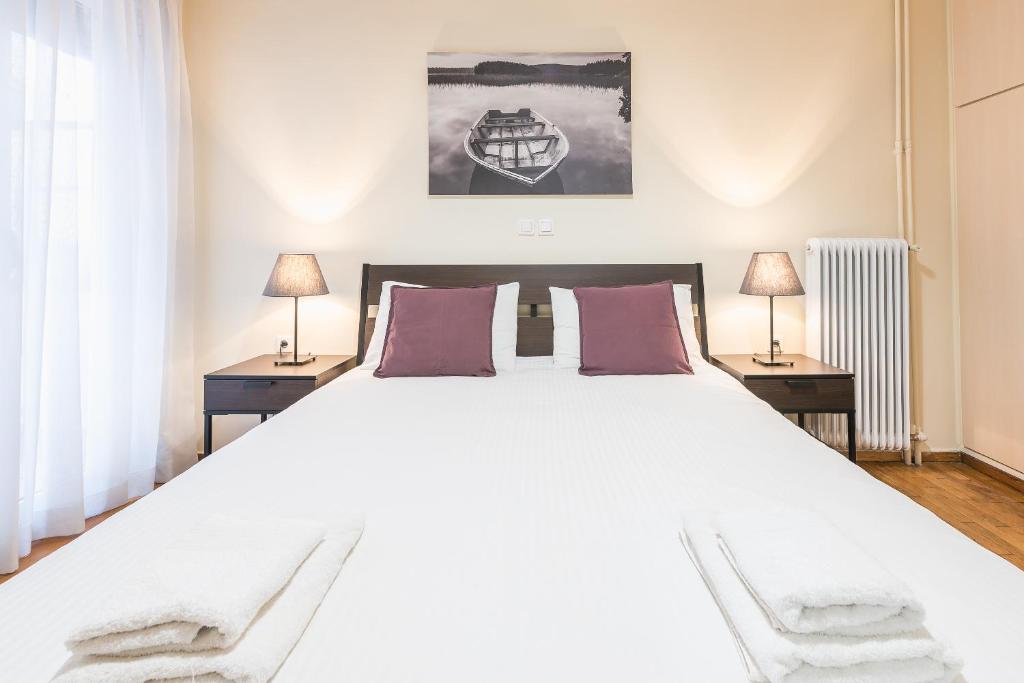 雅典Ioannis Cozy Apartment 500 meters from Acropolis museum的卧室配有一张带两张桌子的大型白色床