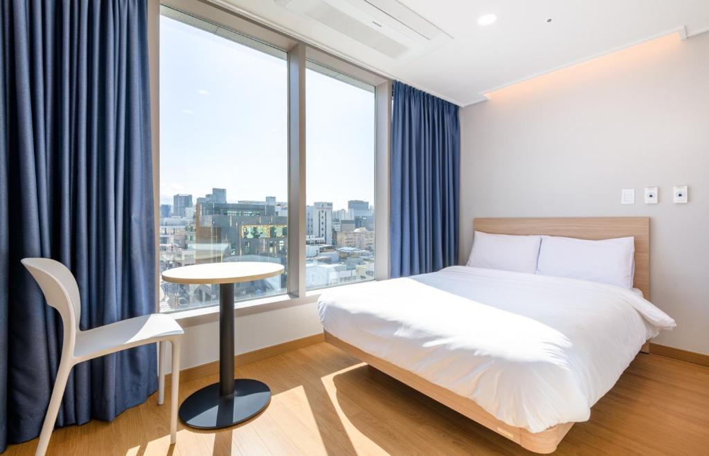 济州市Hi Residences的卧室配有床、桌子和窗户。
