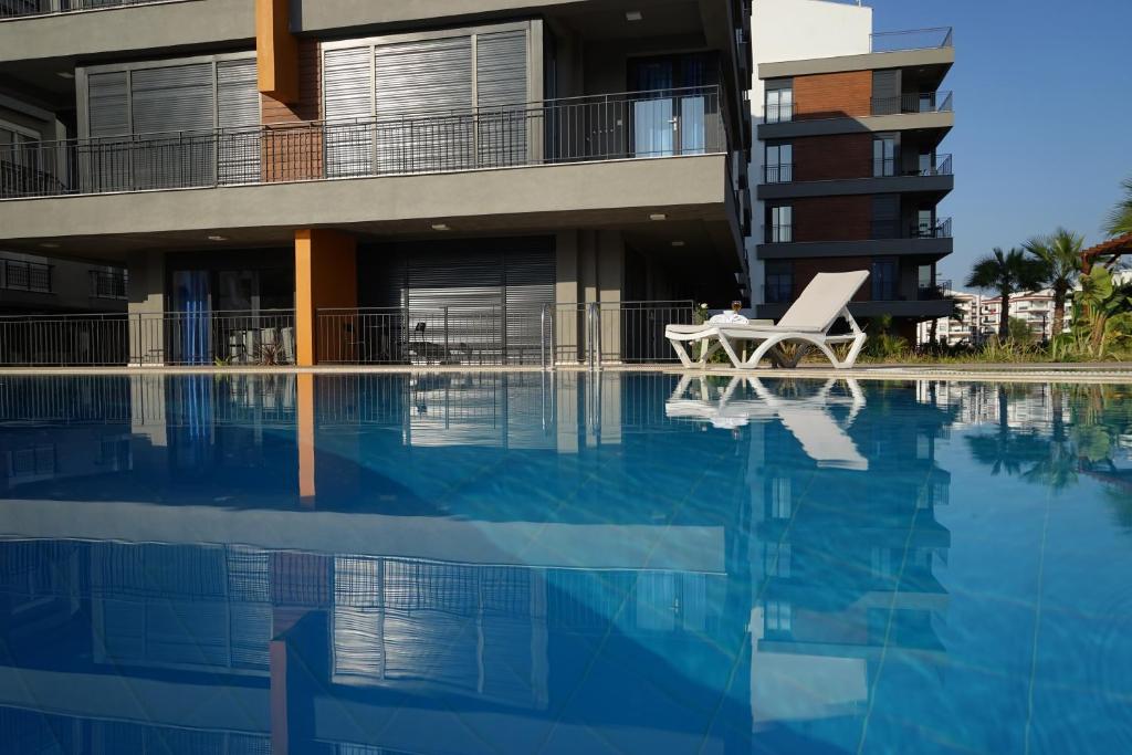 安塔利亚MENE SUITES的一座游泳池,旁边是一座建筑,配有椅子