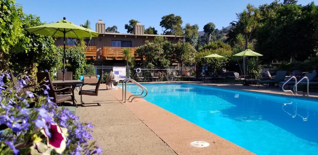 卡梅尔瓦利卡梅尔谷旅舍的一个带桌子和遮阳伞的游泳池
