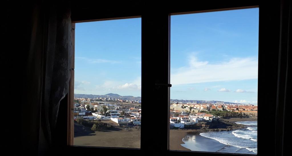 Playa del HombreSanmao的两扇窗户享有海滩和建筑的景致