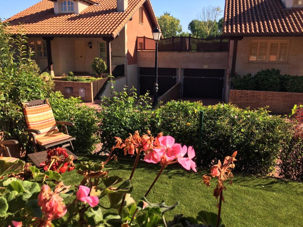 柯米拉斯Las Martas的一座带粉红色花卉、椅子和房子的院子