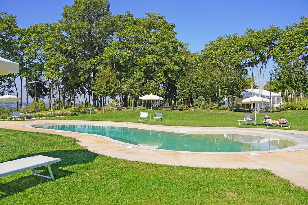 明乔河畔的瓦雷奇奥Agricampeggio Corte Tonolli的一个带长椅和遮阳伞的公园内的游泳池