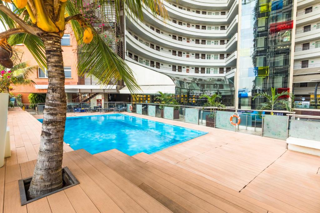 卡利Hotel Spiwak Chipichape Cali的一座位于大楼中间的游泳池,里面种有棕榈树
