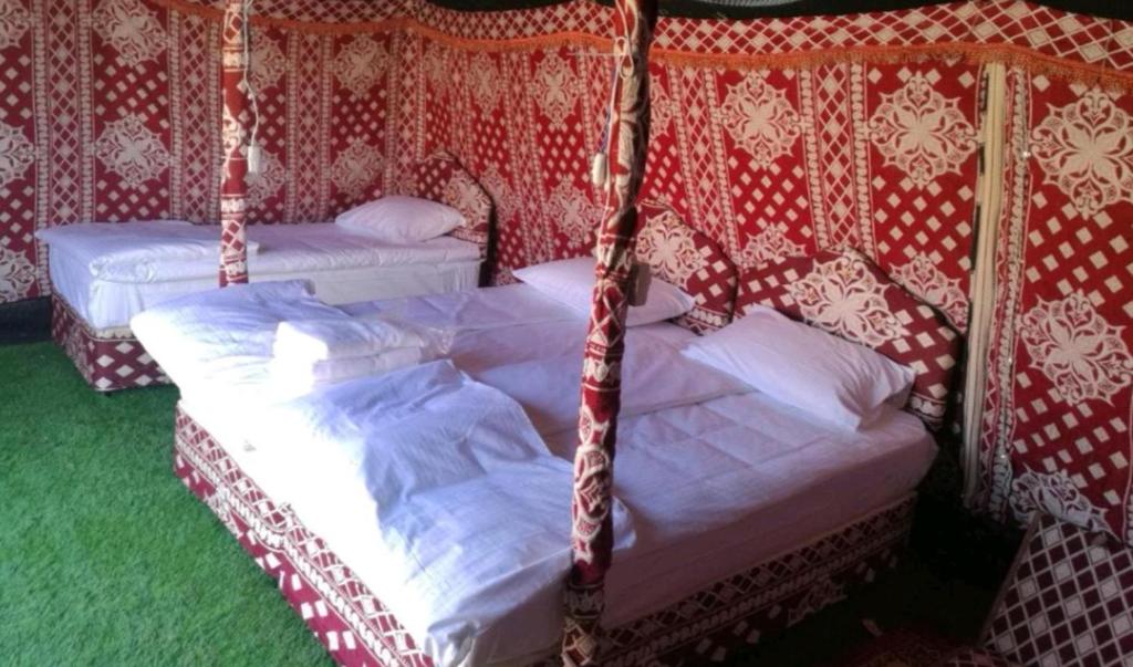 ShāhiqCrescent Desert Private Camp的红色和白色壁纸客房内的两张床