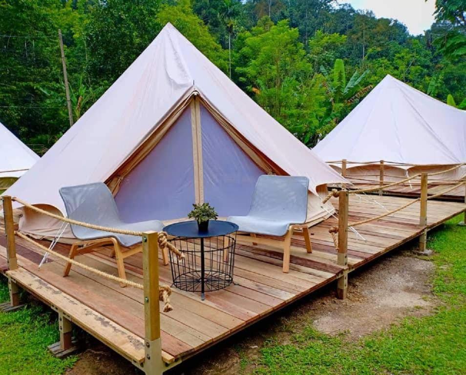 Kampong Sum SumCanopy Villa Glamping Park的帆布帐篷,配有椅子和木甲板上的桌子