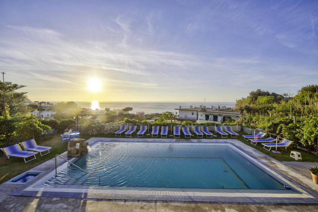 伊斯基亚Hotel Villa Cimmentorosso的一个带躺椅的游泳池,享有日落美景