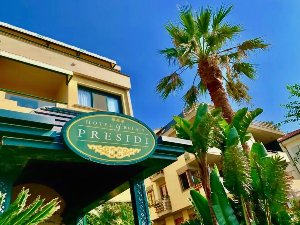 奥尔贝泰洛Hotel Relais I Presidi的棕榈树建筑前的酒店标志