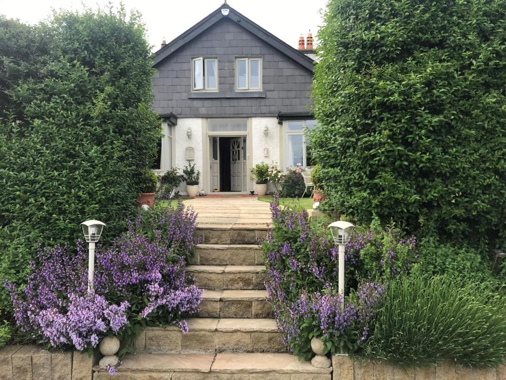 萨顿都柏林艺术家住宿加早餐旅馆的一座带紫色花卉和楼梯的花园的房子