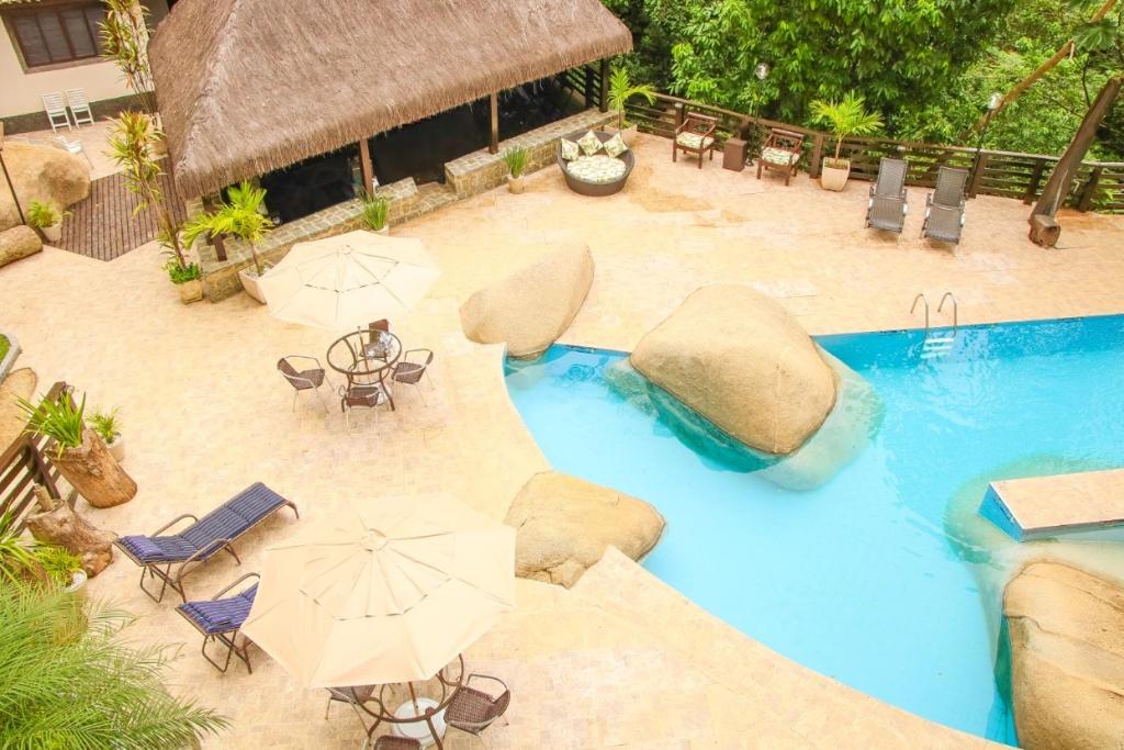 里约热内卢Casa Pedra Bonita的享有带遮阳伞和椅子的游泳池的顶部景致