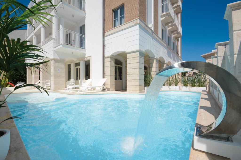 阿尔巴·阿德里亚蒂卡Residence Hotel Alba Palace的一座建筑前的带喷泉的游泳池