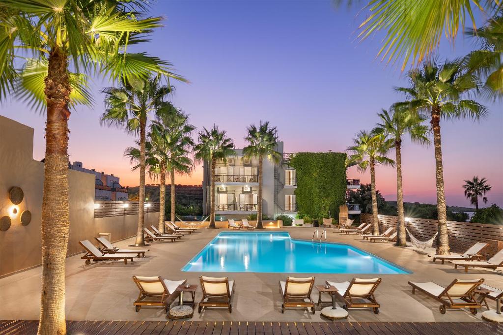 加藤-达拉特索Sea View Hotel & Apartments的一座建筑前的游泳池,里面设有椅子和棕榈树