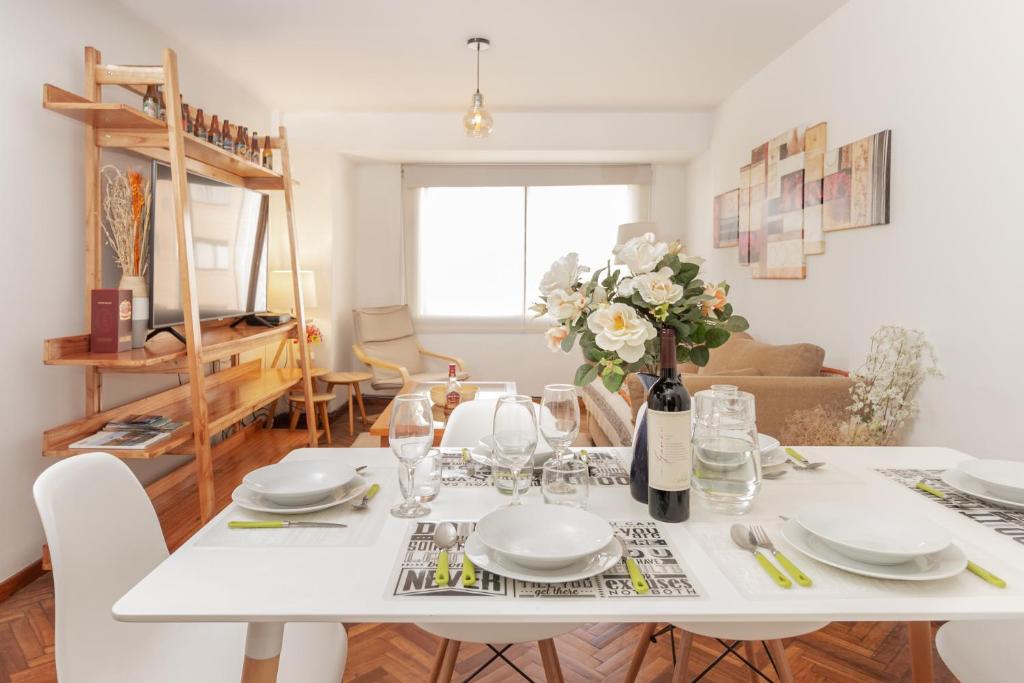 圣卡洛斯-德巴里洛切Tu Apart En Bariloche 2的白色的餐桌,配以白色的盘子和鲜花
