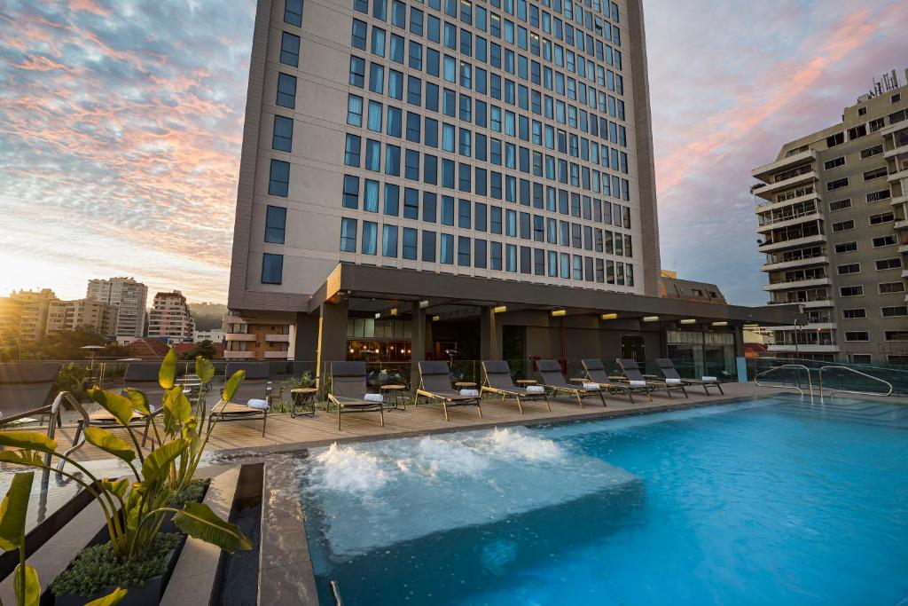 维纳德马Novotel Vina del Mar的酒店游泳池设有椅子,酒店大楼