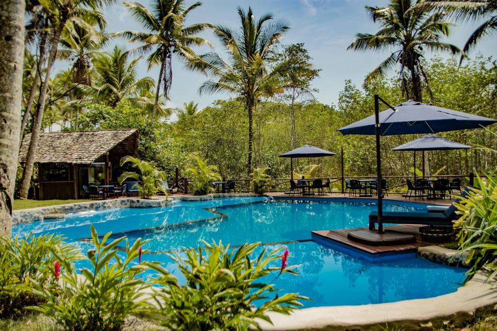 伊塔卡雷巴伊亚州环保度假酒店的度假村的游泳池,配有椅子和遮阳伞