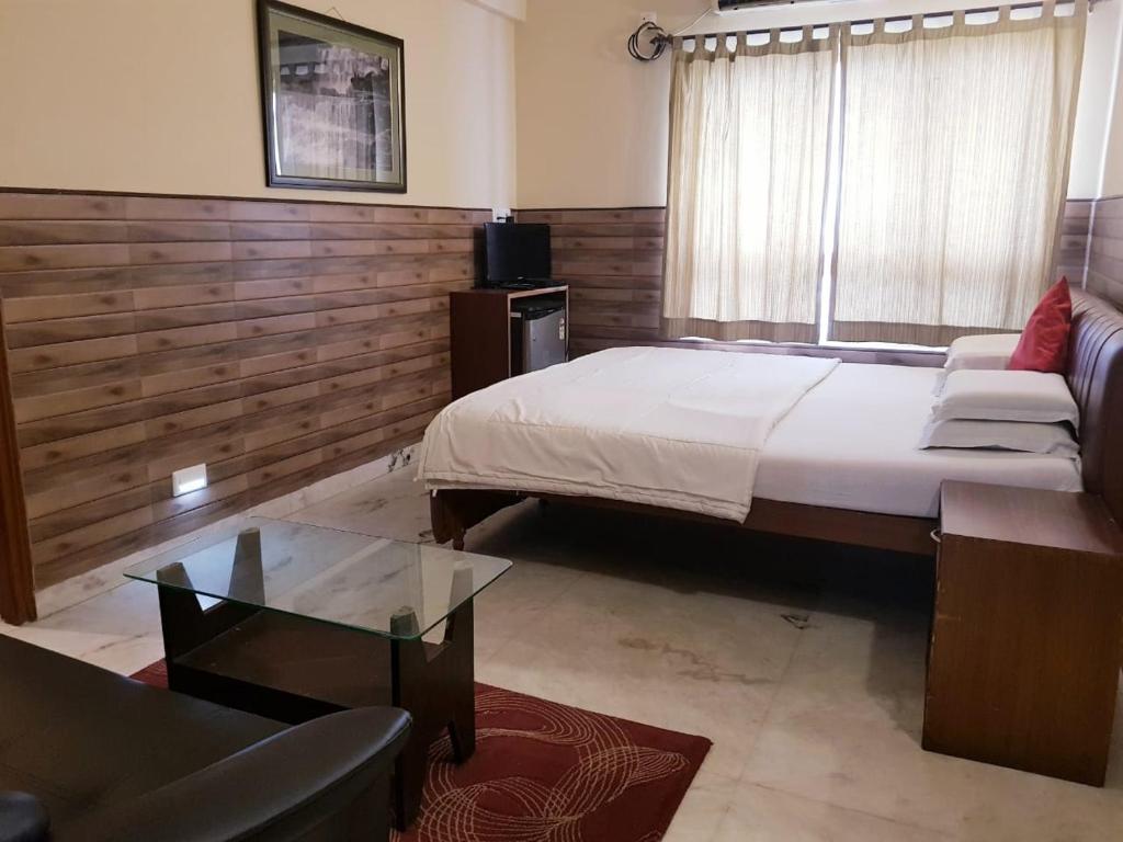 加尔各答Malik Guest House的一间卧室设有一张大床和一张玻璃桌