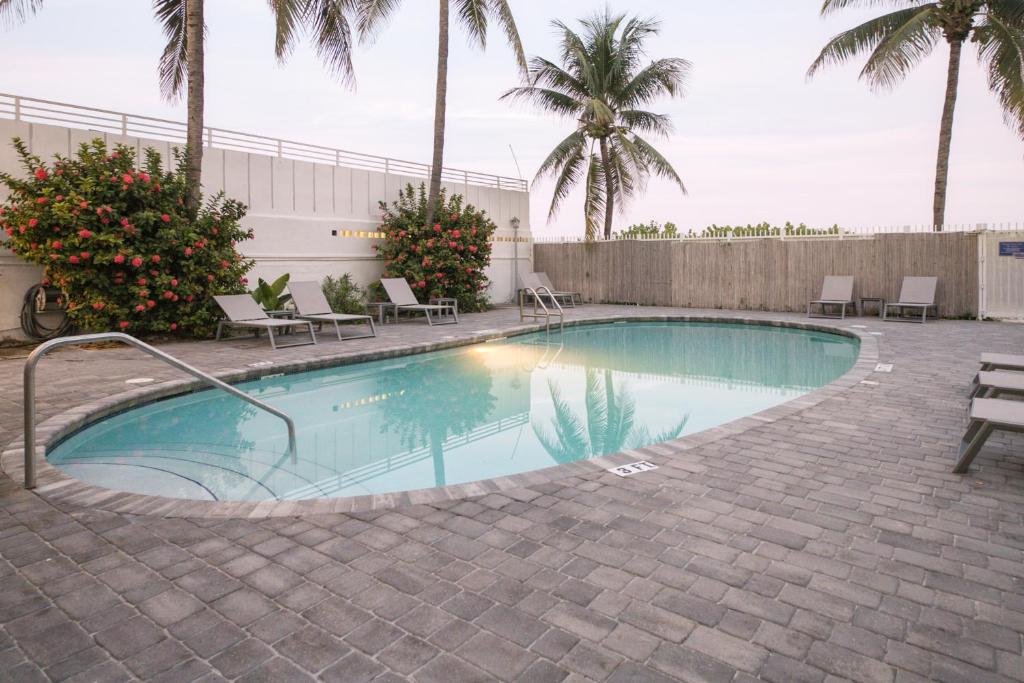 迈阿密海滩Ocean Drive Apartments的一个带椅子的游泳池,棕榈树