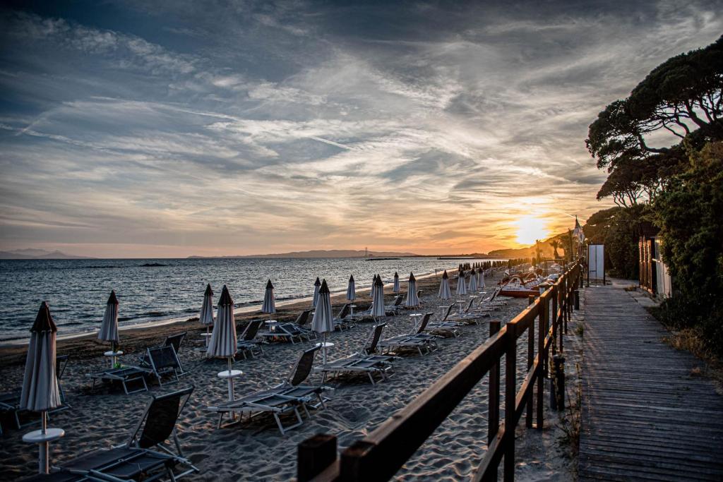 福洛尼卡Golfo del Sole Holiday Resort的海滩上的一组椅子和遮阳伞
