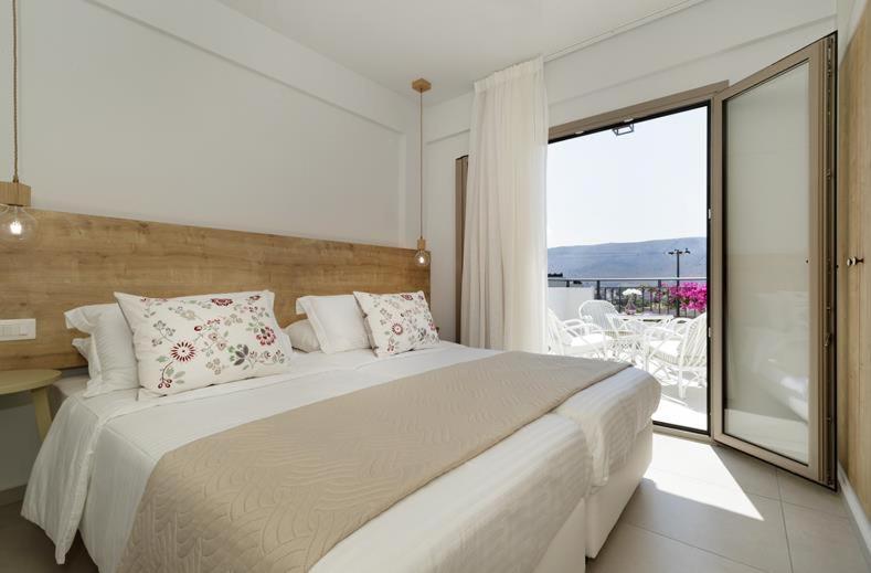 阿默达拉-伊拉克利翁米诺雅公寓酒店的一间带大床的卧室和一个阳台