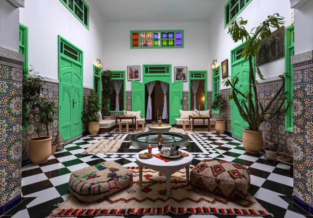 马拉喀什里亚德洛斯梅尔雅姆旅馆的客厅铺有绿色和白色的地板,配有桌子