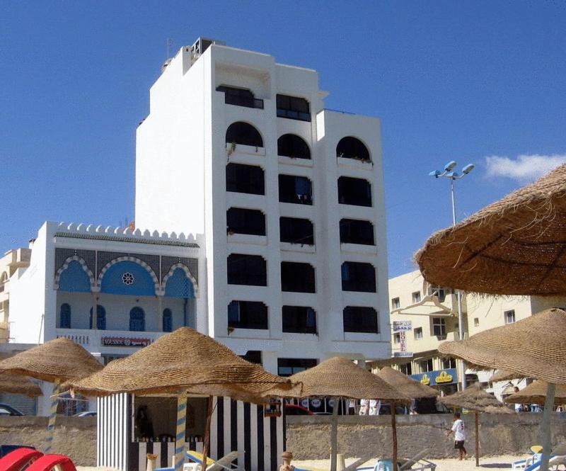 苏塞布杰法住宅酒店的海滩前的白色建筑,带草伞
