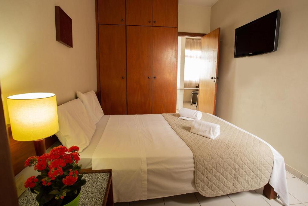 贝洛奥里藏特潘普哈公寓式酒店的卧室配有白色床、灯和鲜花