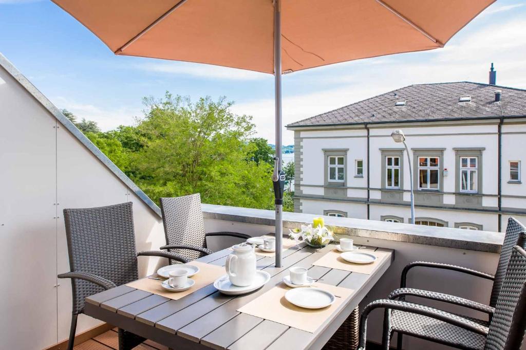 博登斯边的拉多夫采尔Haus Behr am See的阳台配有桌椅和遮阳伞