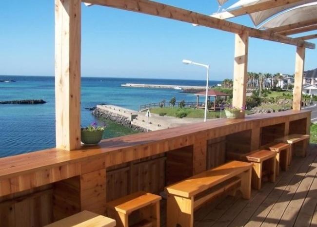 济州市Africa Guesthouse的木甲板设有长椅,享有海景