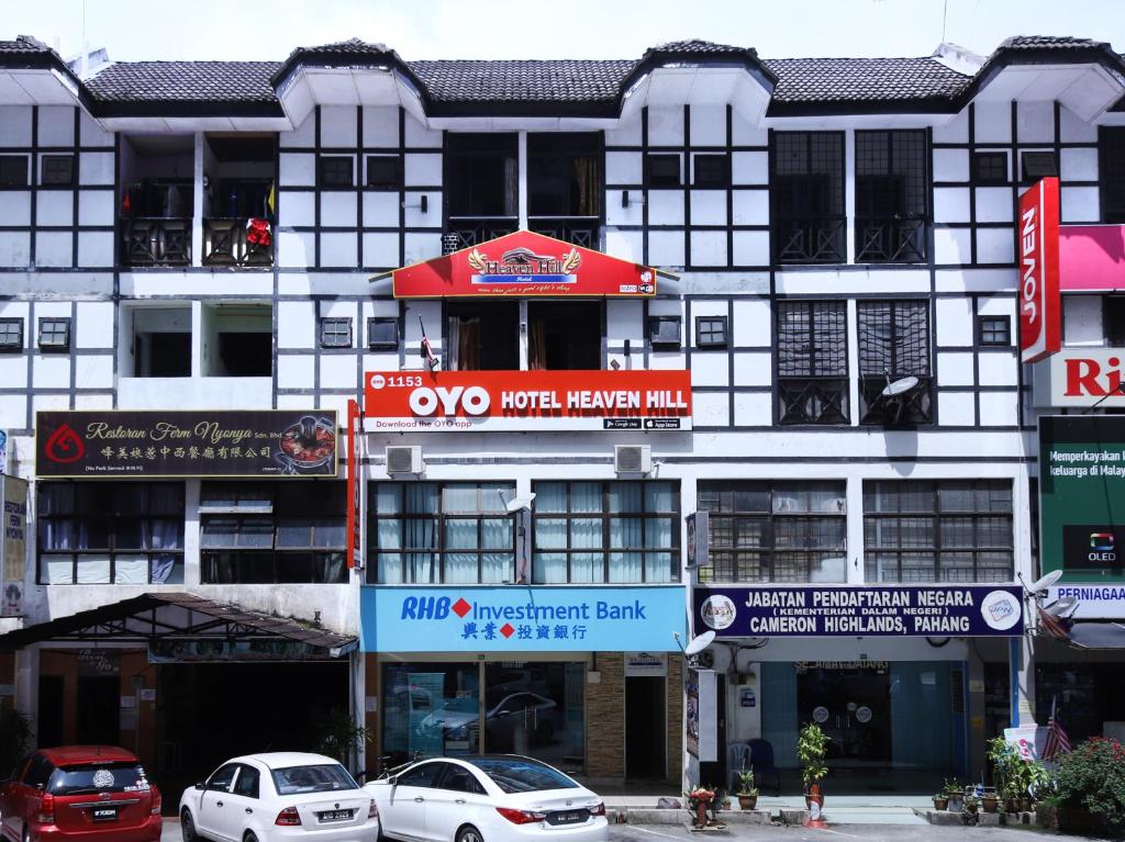 金马仑高原Super OYO 1153 Heaven Hill Hotel 1的一座白色的大建筑,前面有汽车停放