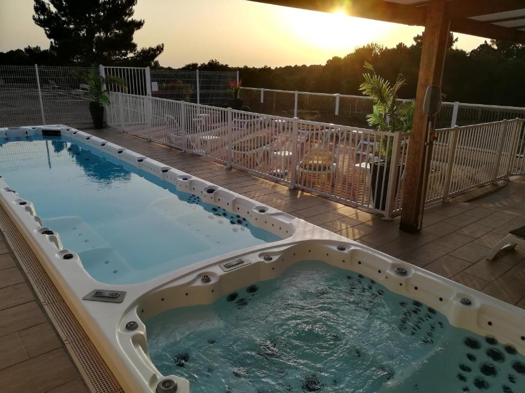 多维勒Hotel Restaurant Logis Le Tropicana的露台的热水浴池,享有日落美景