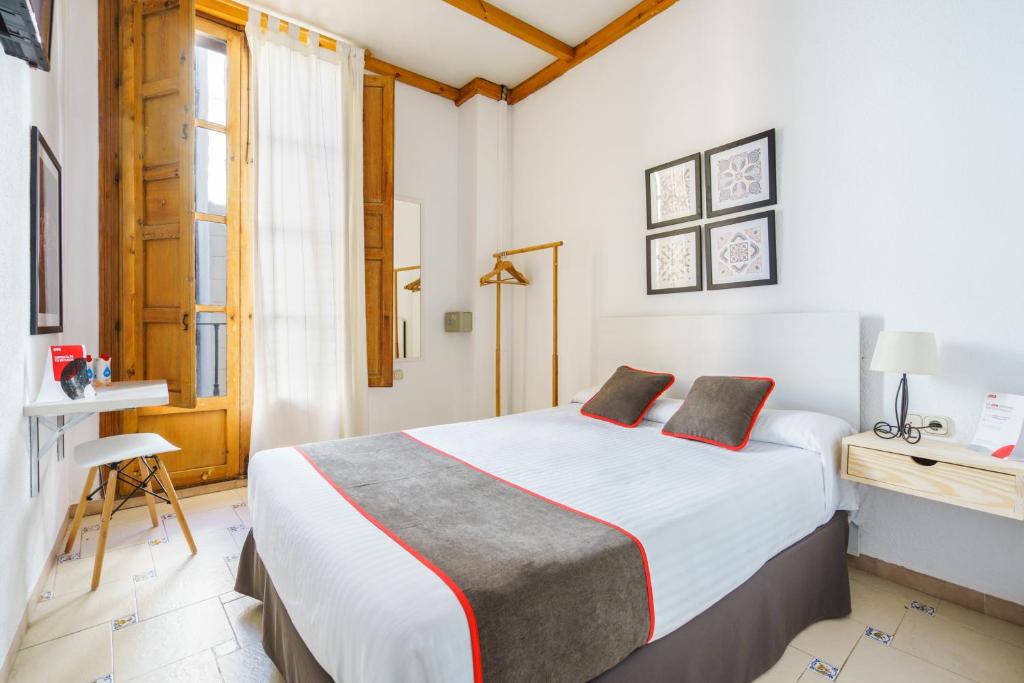 格拉纳达Hostal Austria的一间卧室设有一张大床和一个窗户。