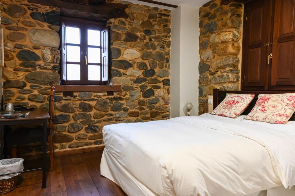 VilladepalosRestaurante - Hotel La Tronera的一间卧室设有石墙、一张床和一个窗口